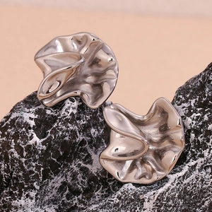 Detailed macro view of silver hammered texture stud earrings on black stone surface