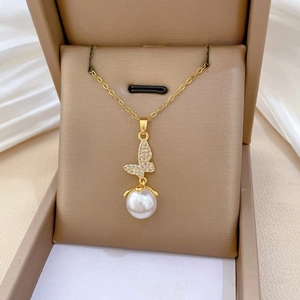 Close-up of sparkling crystal butterfly pendant with a white pearl on a gold chain