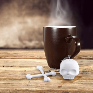 Macro shot of skull and crossbones silicone tea infuser with metal chain on a rustic wooden table