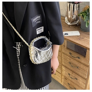 Close-up of silver quilted mini chain bag worn with a black blazer in a modern setting