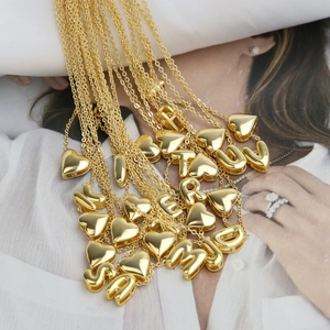 Polished 18k gold brass necklaces with heart and alphabet pendants on fashion magazine