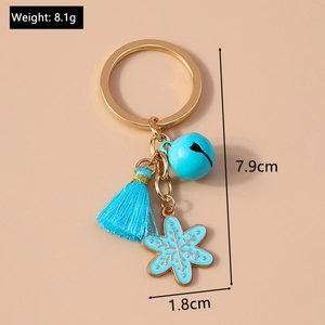Detailed view of Christmas keychain with blue tassel, bell, and snowflake charm