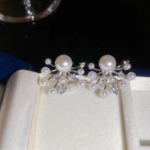 Detailed close-up of fireworks-style earrings with pearls and brilliant zircons on velvet