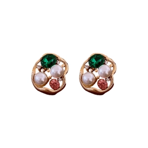 Vintage gold hollow earrings with green gemstone, pearls, and pink crystals on white base