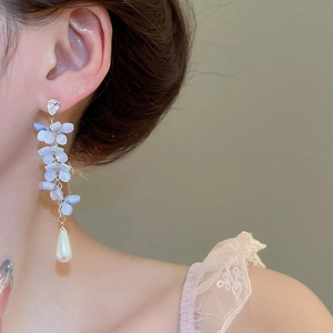 Detail of light blue floral drop earrings with white teardrop pearl on female model