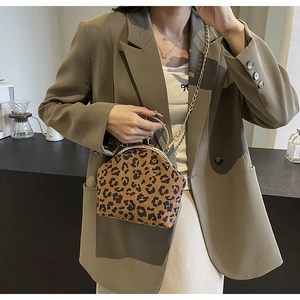 Detail shot of leopard print shell bag with gold chain strap worn by a model