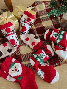 Macro detail of thick coral fleece Christmas socks featuring festive elk and Santa patterns