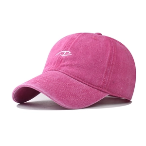 Close-up of embroidered white logo on washed cotton rose red vintage baseball cap