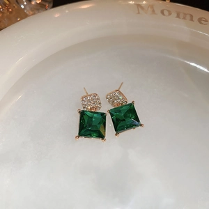 Macro detail of emerald-cut green crystal earrings with rose gold pave diamonds
