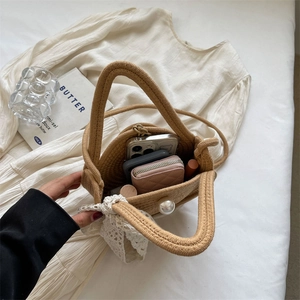 Light brown handmade woven straw bag with pearl buckle and lace bow on white dress