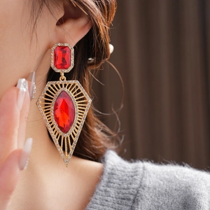 Detail of vintage palace style earrings with red gemstones and gold rhinestone accents