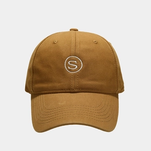 Detailed view of white S letter embroidery on a caramel brown cotton baseball cap