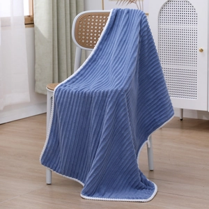 Detailed close-up of blue striped coral fleece towel with white knit hem on a chair