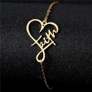 Macro shot of gold stainless steel heart pendant with faith engraving on a black surface