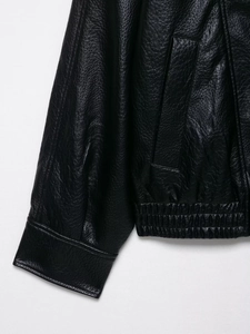 Detailed close-up of elastic cuffs and stitching on a black faux leather street jacket