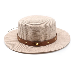 Détail du chapeau de paille beige avec ruban en cuir et rivets dorés décoratifs