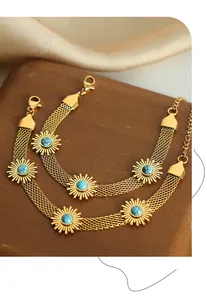 Close-up of golden multi-strand bracelets with turquoise sunburst charms on wood