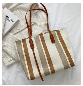 Detailed close-up of vertical stripe knit tote bag with premium leather shoulder straps