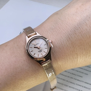 On-wrist view of a rose gold quartz watch with a minimalist dial and mesh strap