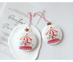 Close-up of white metal Christmas carousel ornament with golden text and red string