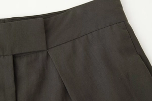 Gros plan sur la texture du sergé gris anthracite et les plis à la taille du pantalon
