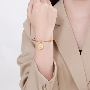 Bracelet jonc ouvert en acier doré avec pendentif soleil porté par un mannequin