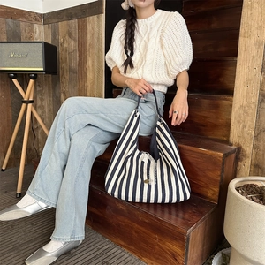 Détail du sac cabas en toile rayée avec un nœud en dentelle et une poignée tissée