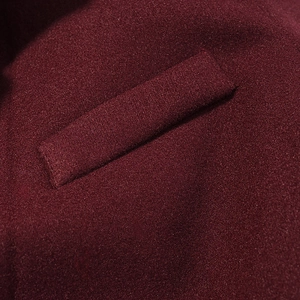 Close-up of deep wine red wool fabric texture and stitching detail on a winter coat