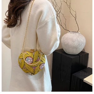 Detail of heart-shaped evening bag with yellow sequin floral embroidery and gold chain