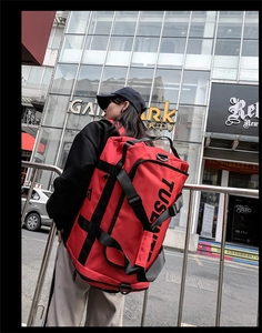 Close-up of red Oxford fabric backpack with bold black lettering and side strap detail