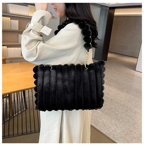 Plush black tote bag with chain strap styled on model in beige coat for autumn