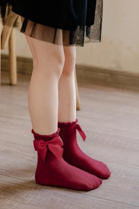 Detail of burgundy girl's cotton socks featuring satin side bows and scalloped cuffs