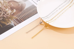 Detail of gold and silver stainless steel necklaces displayed on a white plate and magazine