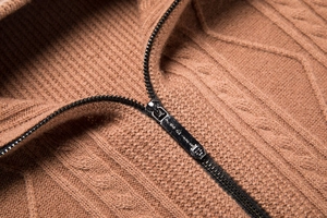 Detail of metal zipper and cable-knit texture on brown men's cardigan collar