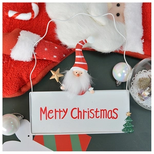 Close-up of a white iron Christmas sign with Merry Christmas text and Santa Claus doll
