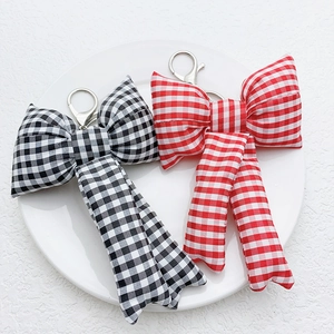Pink and blue plaid fabric bow keychains in a white tray for bag accessory decoration