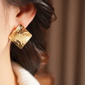 Minimalist 18k gold plated square earrings with hammered texture shown on a model's ear