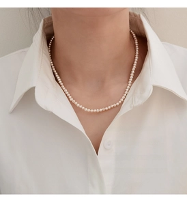 Close-up of model wearing 3-4mm natural pearl necklace with soft pink luster and white shirt