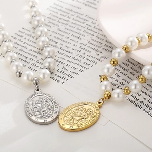 Pendentifs Saint-Christophe sur colliers de perles en or et argent sur un livre ouvert