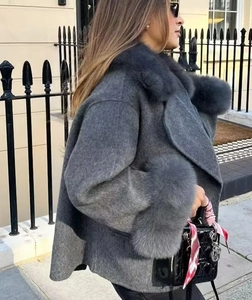 Detail of elegant grey wool coat featuring faux fur collar and cuffs in outdoor setting