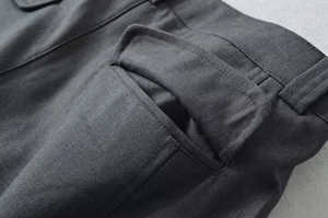 Detailansicht der dunkelgrauen Hose mit Twill-Textur und Nähten der Taschenklappe
