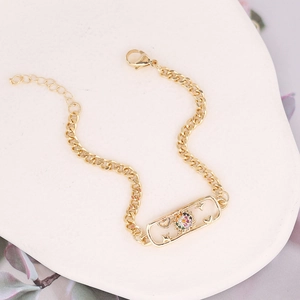 Macro detail of gold-plated sun and heart charm bracelet with multicolor cubic zirconia
