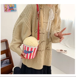 Sac à bandoulière en peluche en forme de pop-corn porté avec un pull en maille beige
