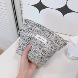 Close-up of black and white tweed makeup bag featuring the simple wish woven label