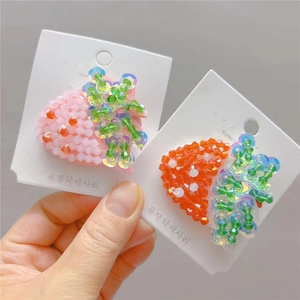 Detail of handmade beaded hair clips with cute strawberry and carrot fruit designs