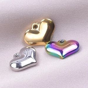 Polished stainless steel heart pendants in gold, silver, and rainbow finishes on silk fabric