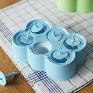 Detailed top view of a 6-hole blue silicone ice pop mold on a blue checkered cloth