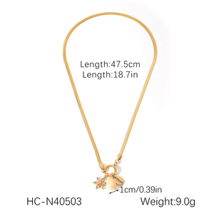 Detailed view of golden snake chain necklace with floral and coffee bean pendants and specs