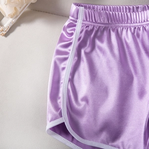 Detail of purple satin sports shorts with white piping and silky fabric texture