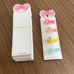 Detailed view of long white paper hair clip display card with four colorful kids barrettes